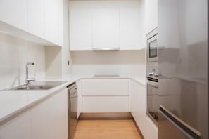 A compact kitchen with white cabinetry, a stainless steel refrigerator, and a built-in oven. - Apartments Hotel Sant Pau (Barcelona)