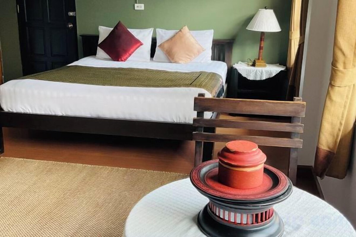 A bed with pillows, a bedside table with a lamp, and a chair.