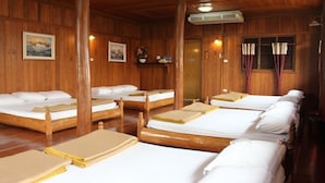 A room with wooden walls and floors, multiple beds with white linens, and a large window with curtains. - Sangthong Resort (Saraphi)