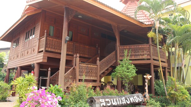 A traditional wooden building with a balcony and staircase, surrounded by tropical plants. - Sangthong Resort (Saraphi)