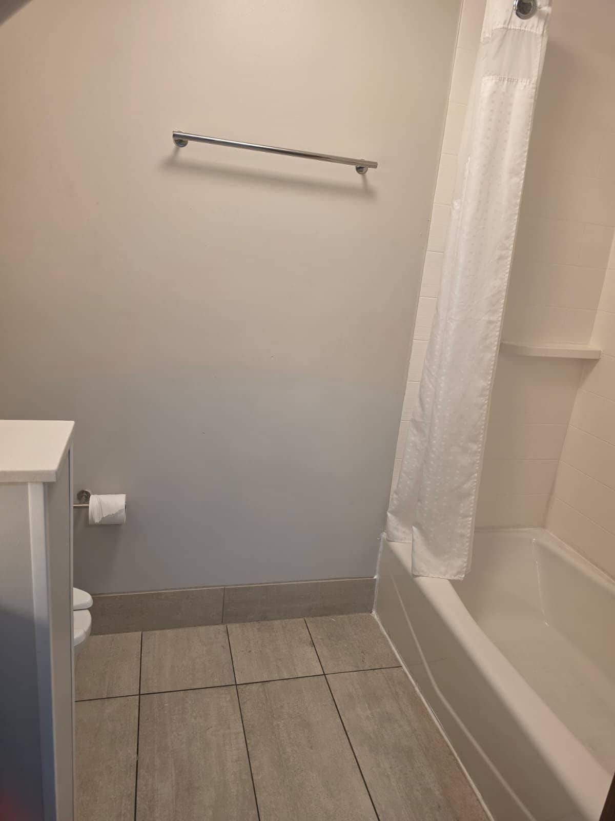 A bathroom with a bathtub, toilet, and a towel rack.