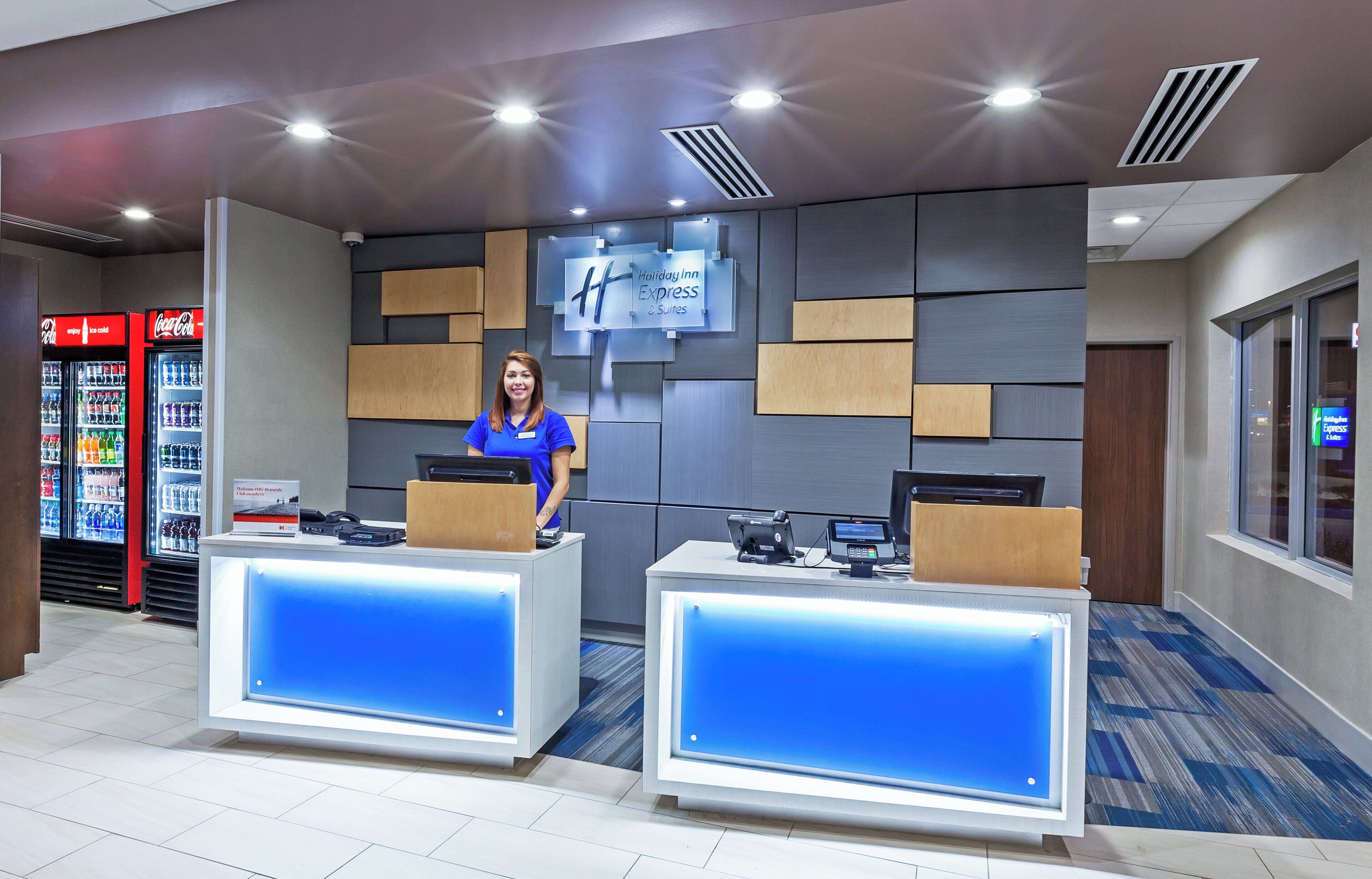 En receptionsdisk med moderne design, et Coca-Cola køleskab og et Holiday Inn Express skilt.