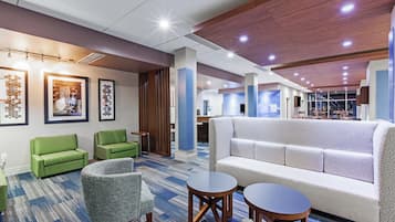 Un hall d’hôtel avec des espaces aménagés pour s’asseoir, un comptoir d’accueil et une grande fenêtre.