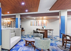 A modern hotel lobby with a seating area, a dining table, and artwork on the walls. - Holiday Inn Express & Suites Tulsa West - Sand Springs by IHG (Sand Springs)