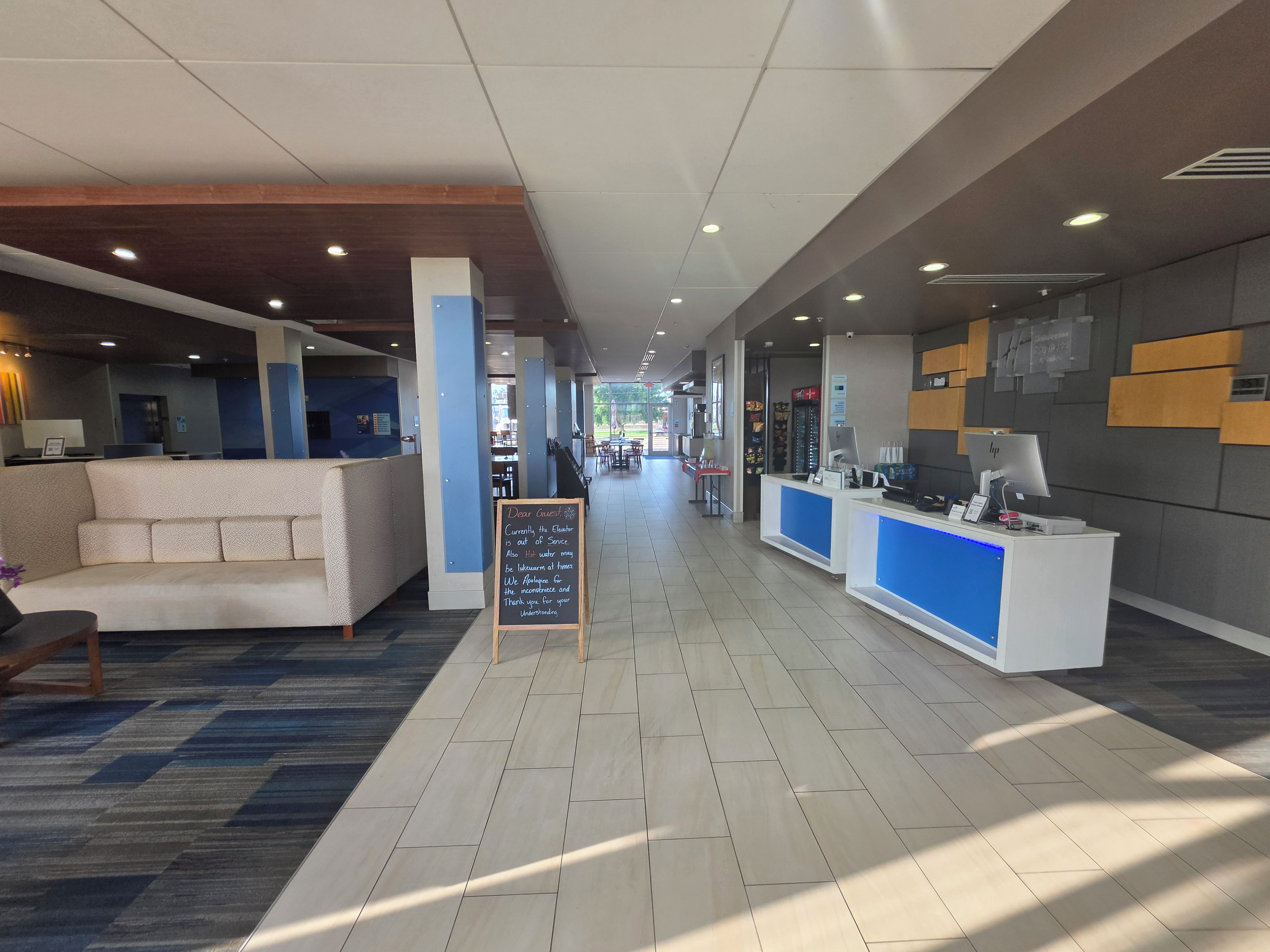A hotel lobby with a reception desk, seating area, and a signboard.