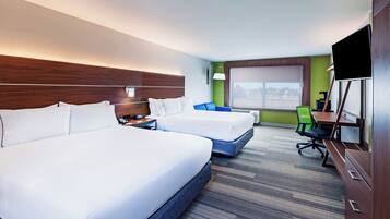 A hotel room with two beds, a desk, a chair, a TV, and a window.