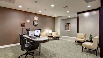 A conference room with a round table, a computer, and four chairs.