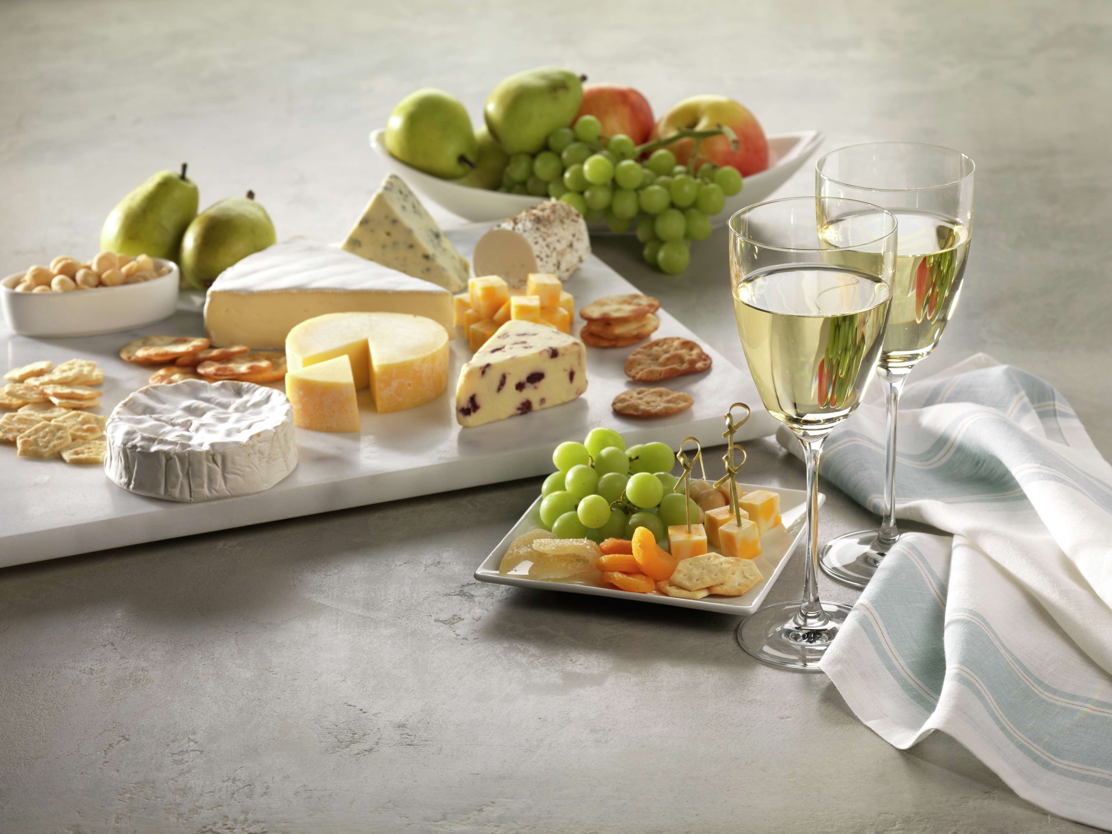 A cheese board with various cheeses, grapes, and crackers.