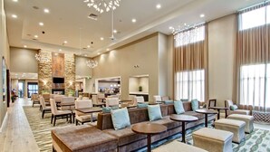 A spacious lobby with seating areas, a fireplace, and large windows. - Homewood Suites by Hilton Clifton Park (Clifton Park)