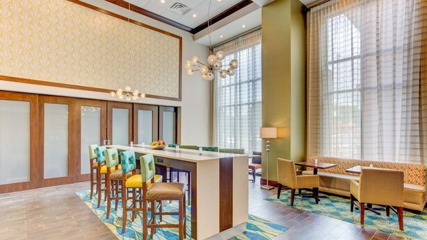 A hotel lobby with a bar area, seating, and large windows. - Hampton Inn & Suites Manchester (Manchester)