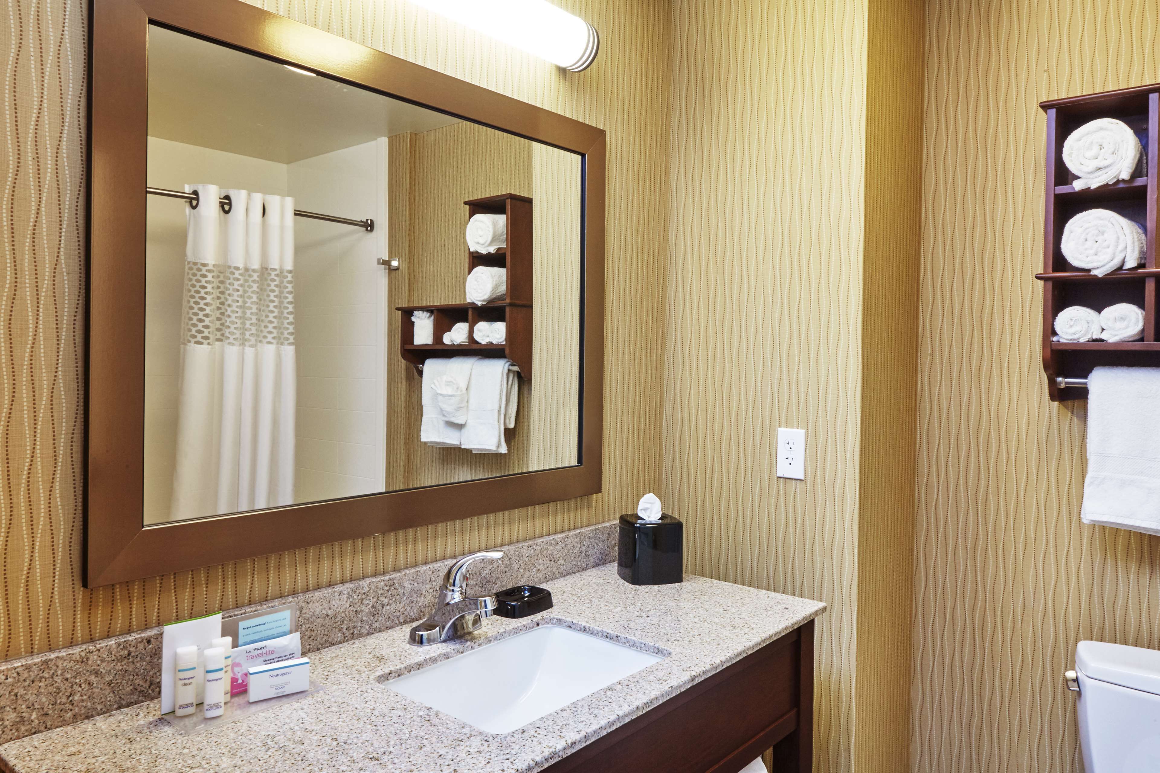 Un bagno con uno specchio grande, un lavandino e un portasciugamani.