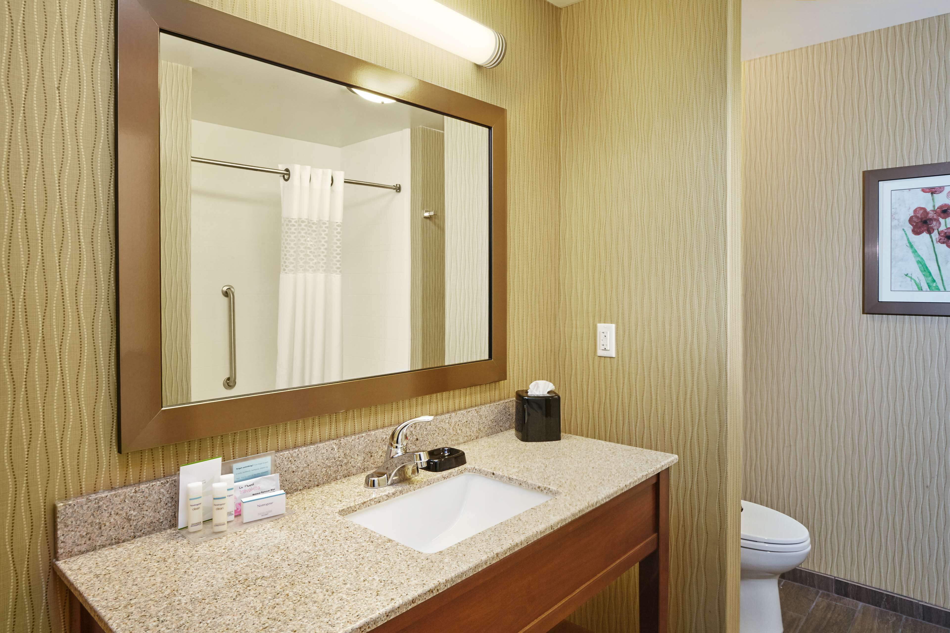 Une salle de bain avec un grand miroir, un lavabo et des toilettes.