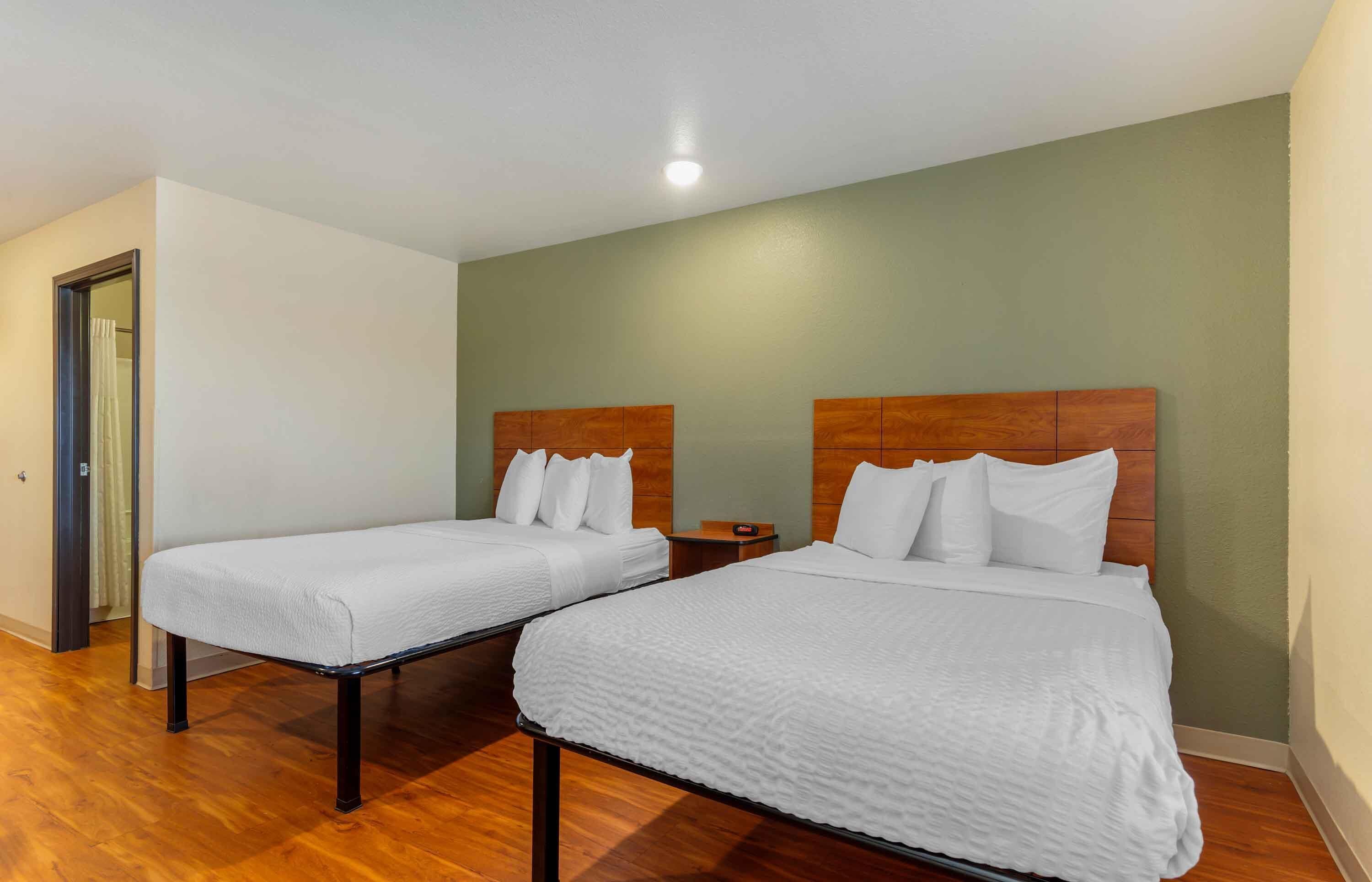 A hotel room with two beds, wooden headboards, and a small bedside table.