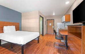 A hotel room with a bed, a desk with a chair, a television, and a kitchenette. - Extended Stay America Select Suites - Atlanta - Chamblee (Chamblee)