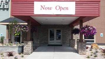 Welcome to our hotel, now open for guests. The entrance features a beautiful stone facade and a charming garden.