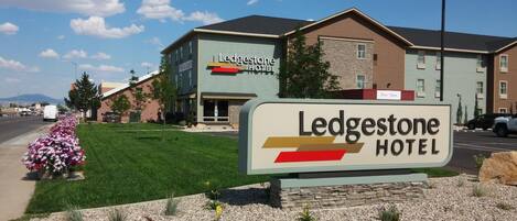 A hotel sign with the name 'Ledgestone Hotel' and a 'Now Open' sign above it.