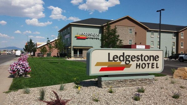 A hotel sign with the name 'Ledgestone Hotel' and a 'Now Open' sign above it.