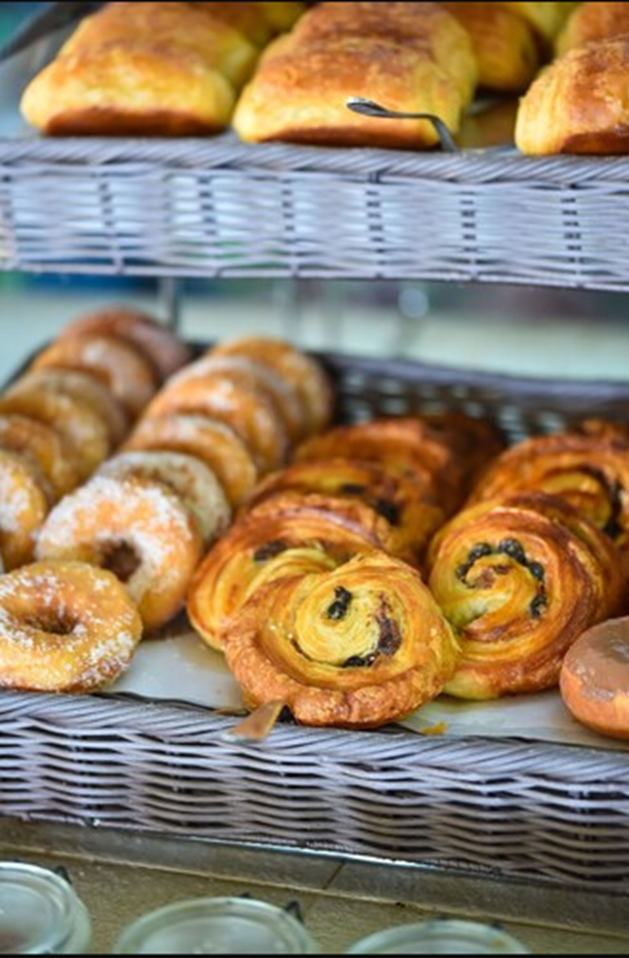 A display of various baked goods, including pastries and bread, arranged on wicker trays.