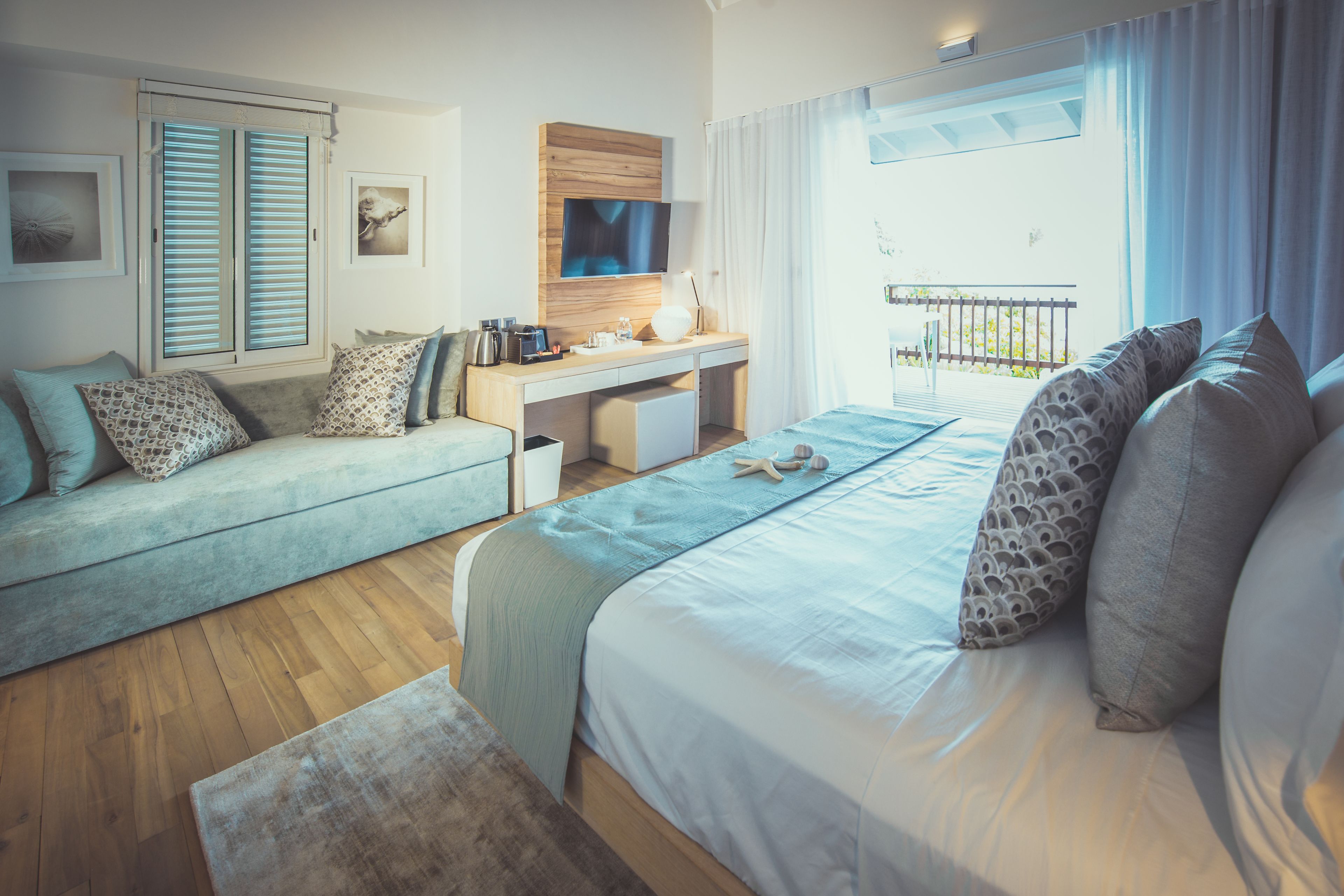 Una habitación de hotel moderna con cama, sofá, escritorio y balcón.