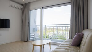 A modern living room with a sofa, a small table, and a TV mounted on the wall. - Jeju Baraki (Seogwipo)