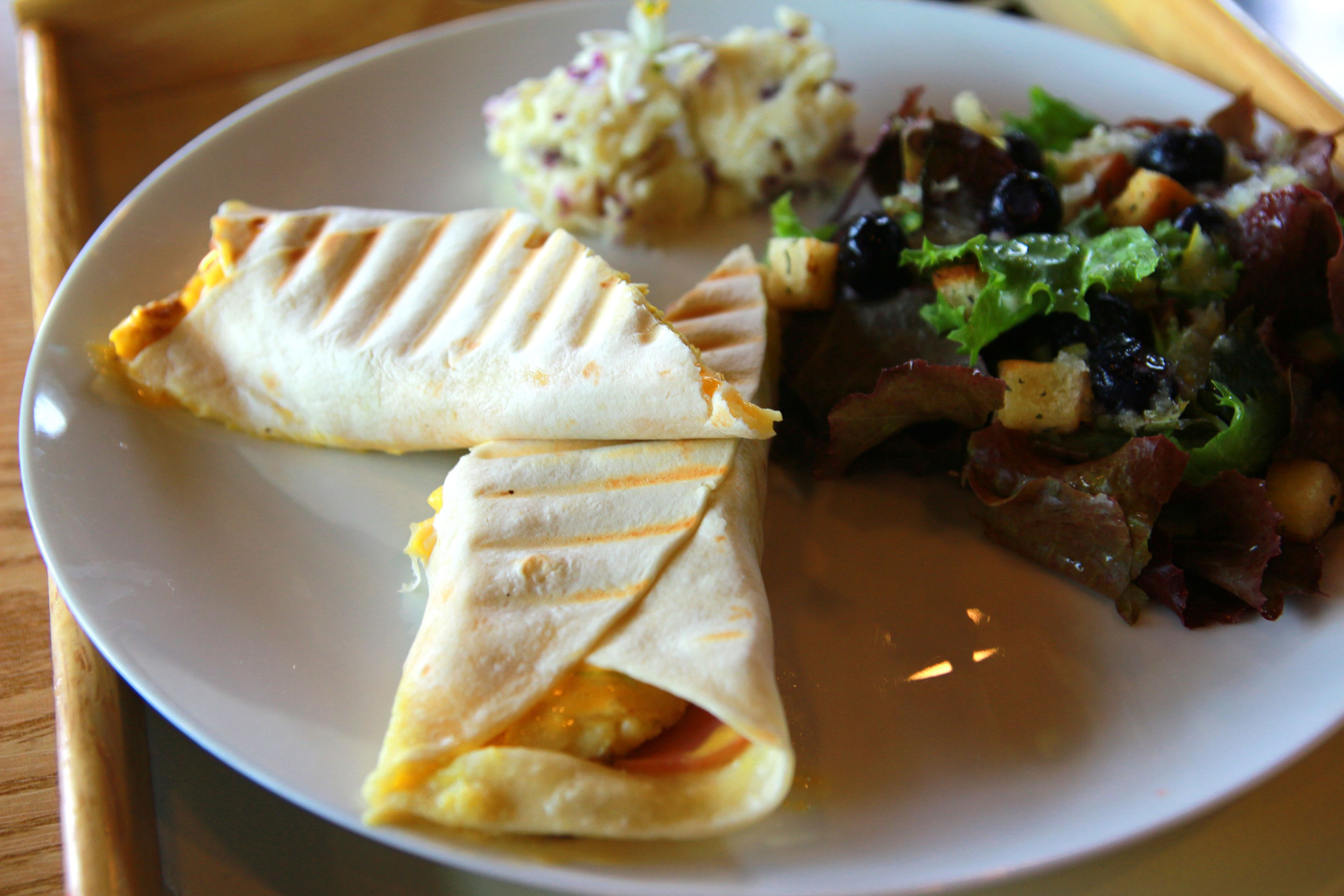 A plate with two quesadillas, a side salad, and a potato salad.