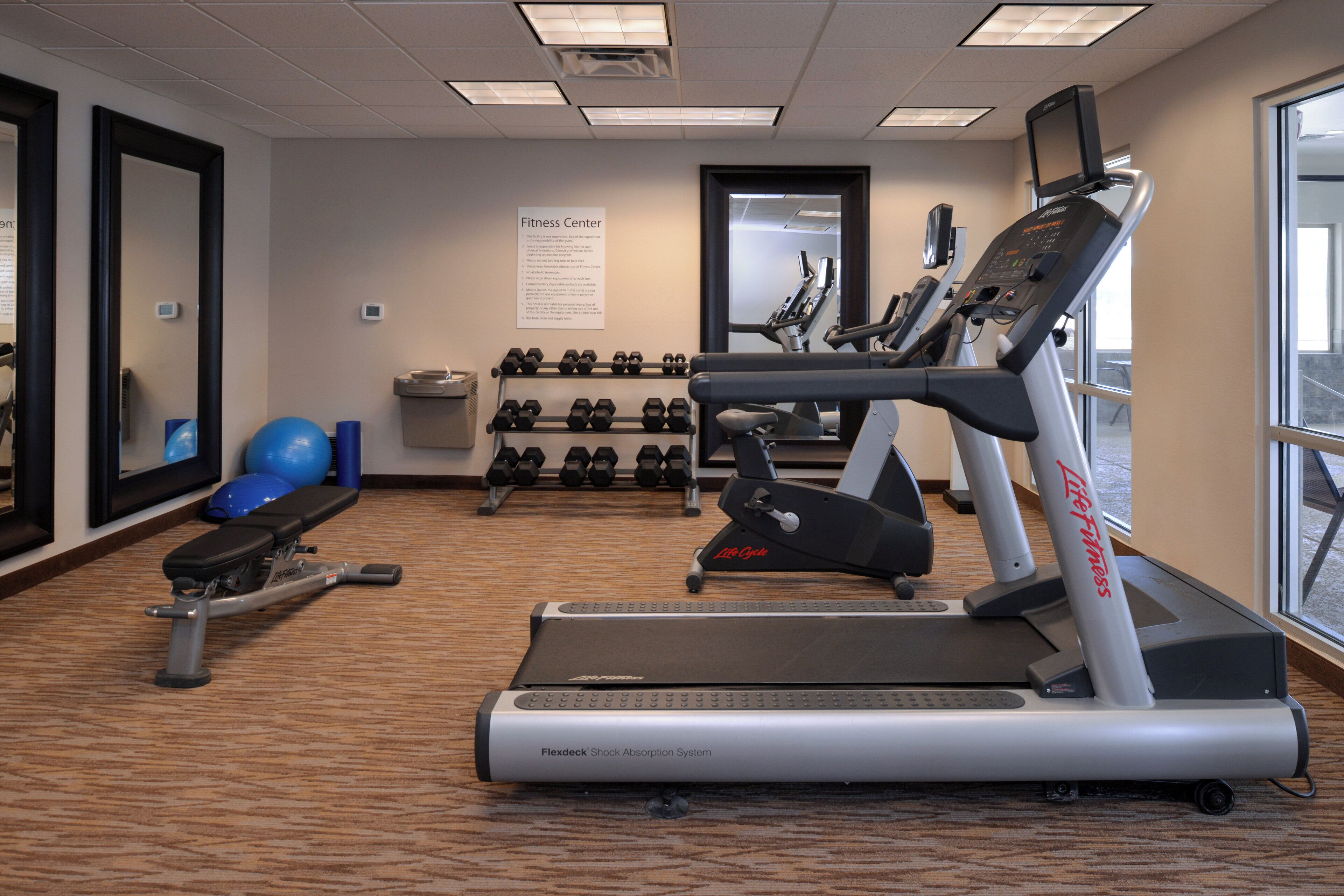 A fitness center with treadmills, dumbbells, and exercise balls.