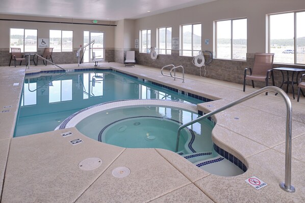 A hotel pool area with a hot tub, lounge chairs, and a lifeguard sign.