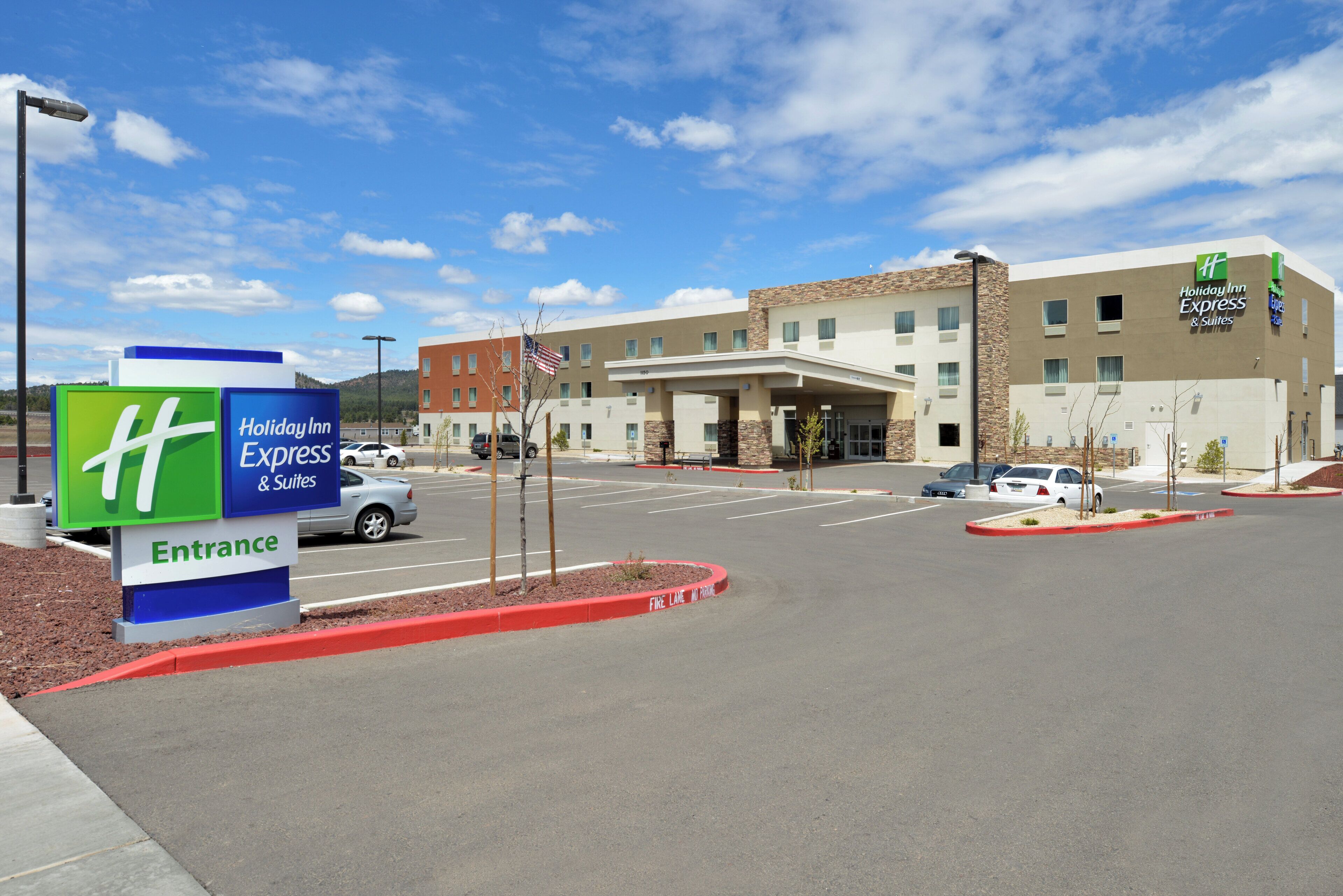 A Holiday Inn Express & Suites building with a clear sky, parking lot, and entrance sign.