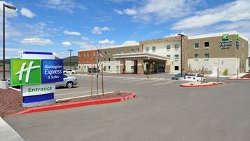 A Holiday Inn Express & Suites building with a clear sky, parking lot, and entrance sign.
