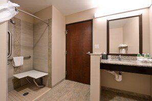 Une salle de bain avec une douche, un lavabo, un miroir et une porte.