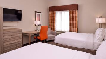 A hotel room with two beds, a desk, a chair, a TV, and a window with curtains.