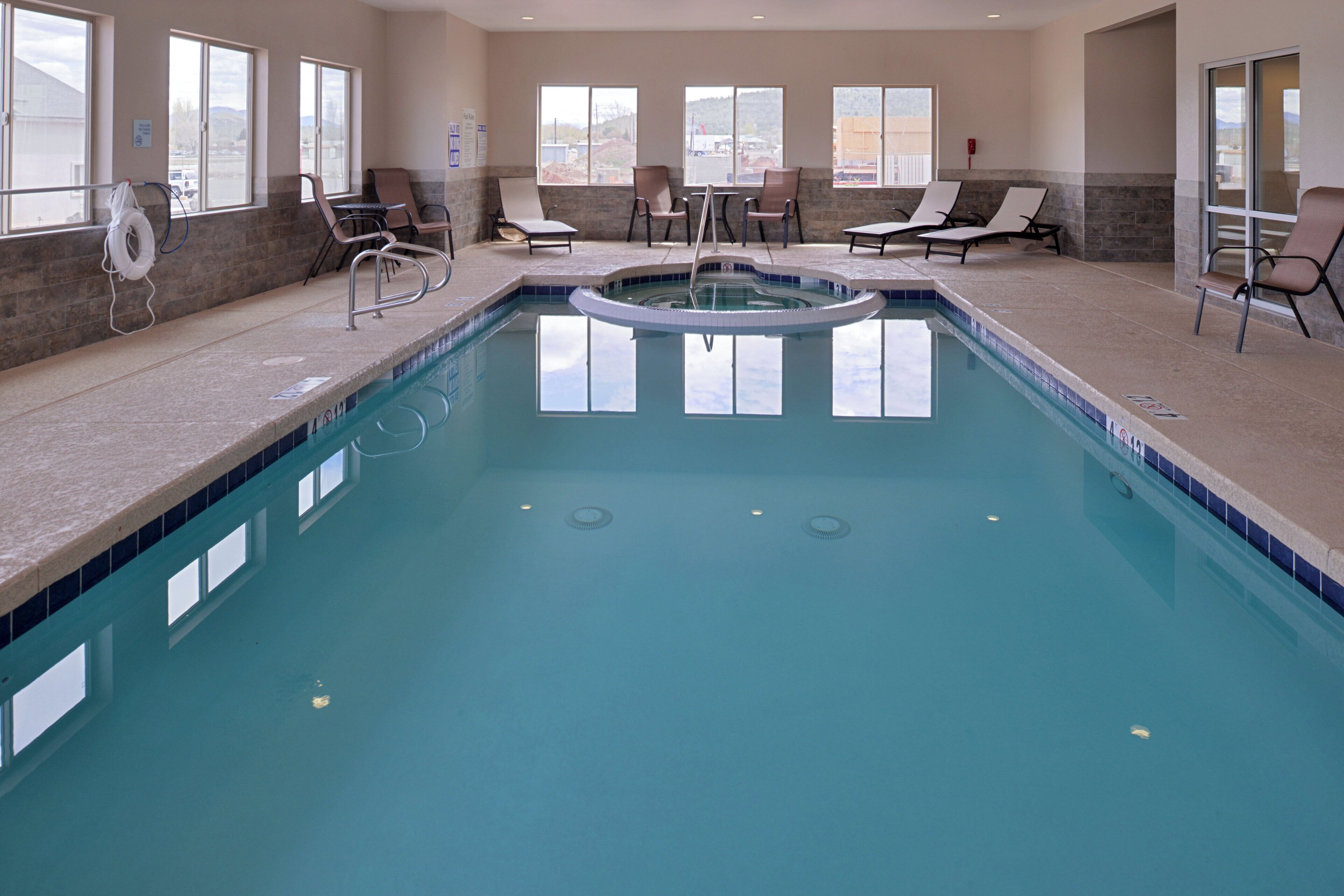 Una piscina con jacuzzi, sillas de descanso y vistas del entorno.