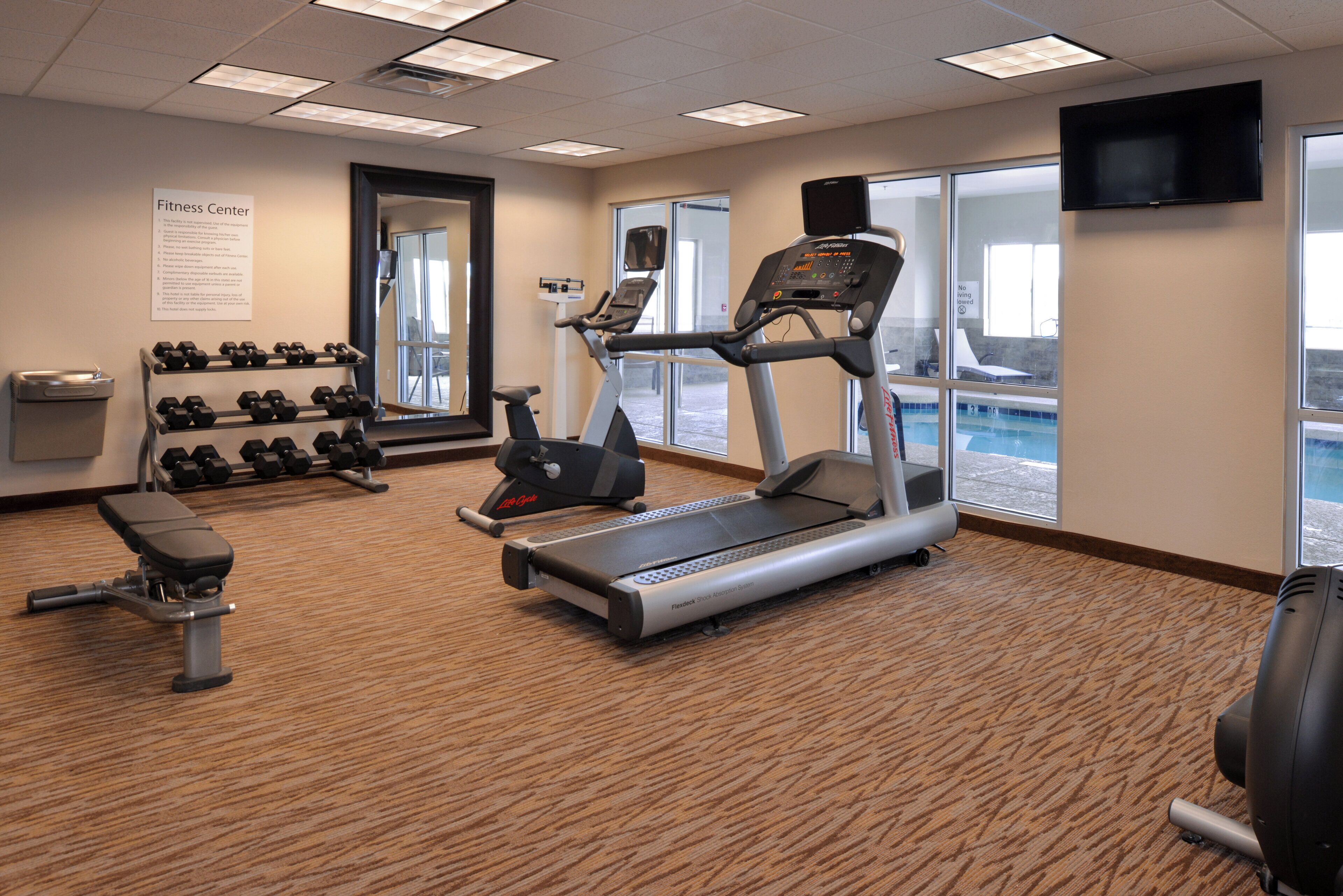 A fitness center with treadmills, dumbbells, and a bench.