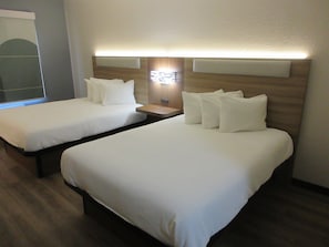 A hotel room with two beds, a nightstand, and a wall-mounted lamp. - Best Western Stanton (Stanton)