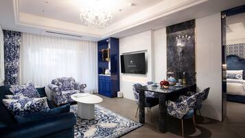 Uma sala de estar moderna com um sofá de padrão azul e branco, uma mesa de centro redonda e um espaço de jantar com uma mesa de mármore escura e cadeiras combinando.