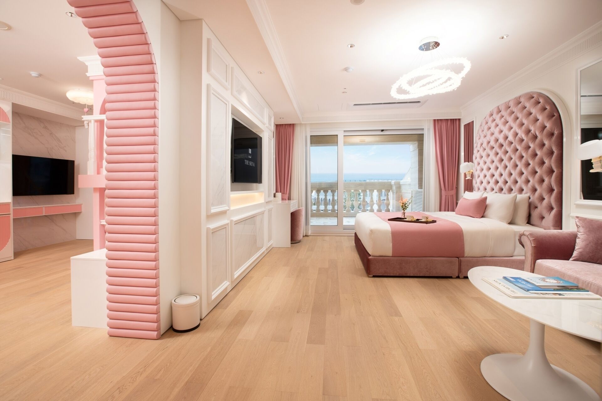 A modern hotel room with a large bed, a seating area, and a balcony with a view.