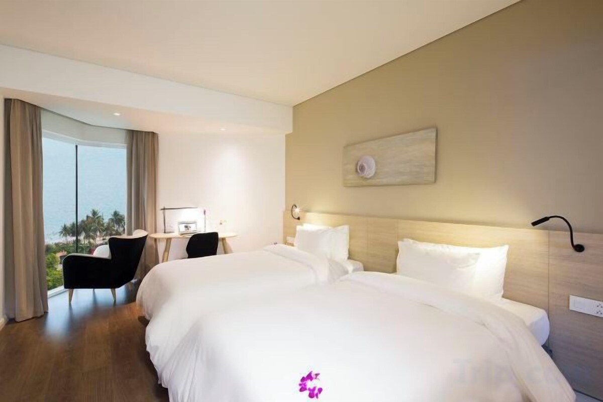 A hotel room with two beds, a desk, and a chair.