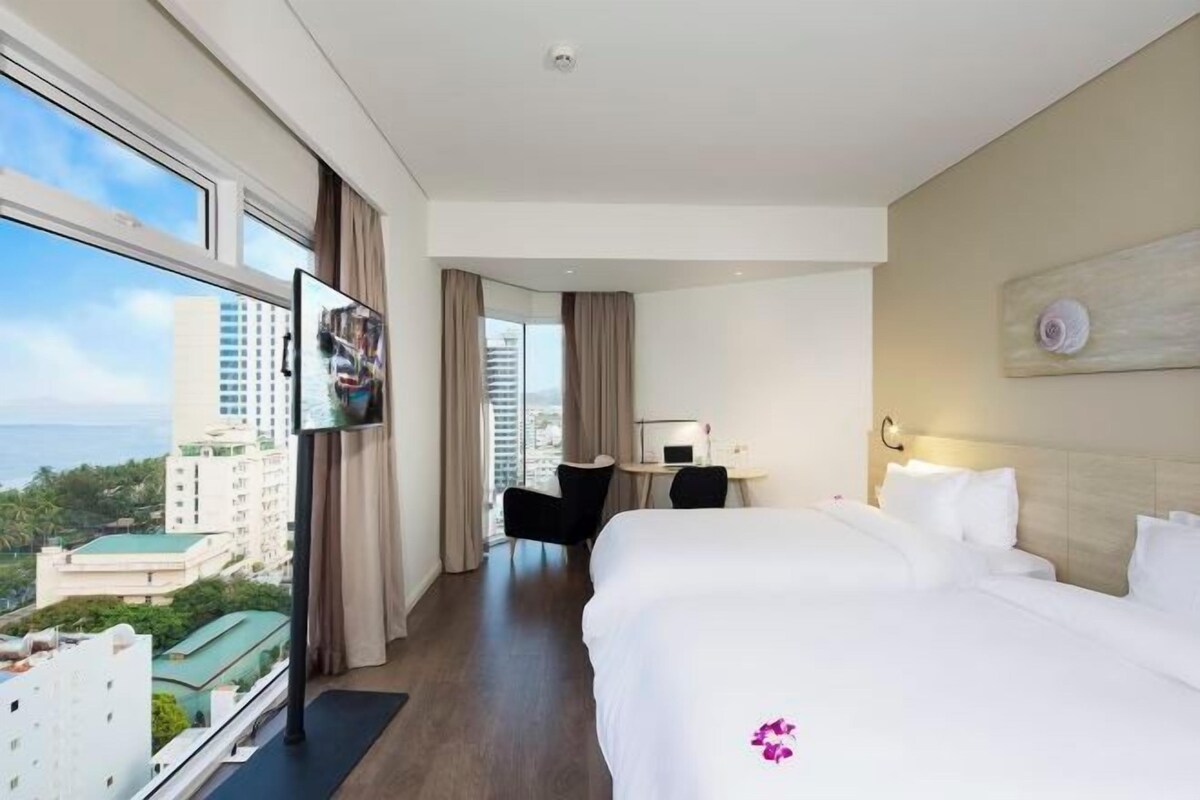 A hotel room with a large bed, a desk, a chair, and a TV.
