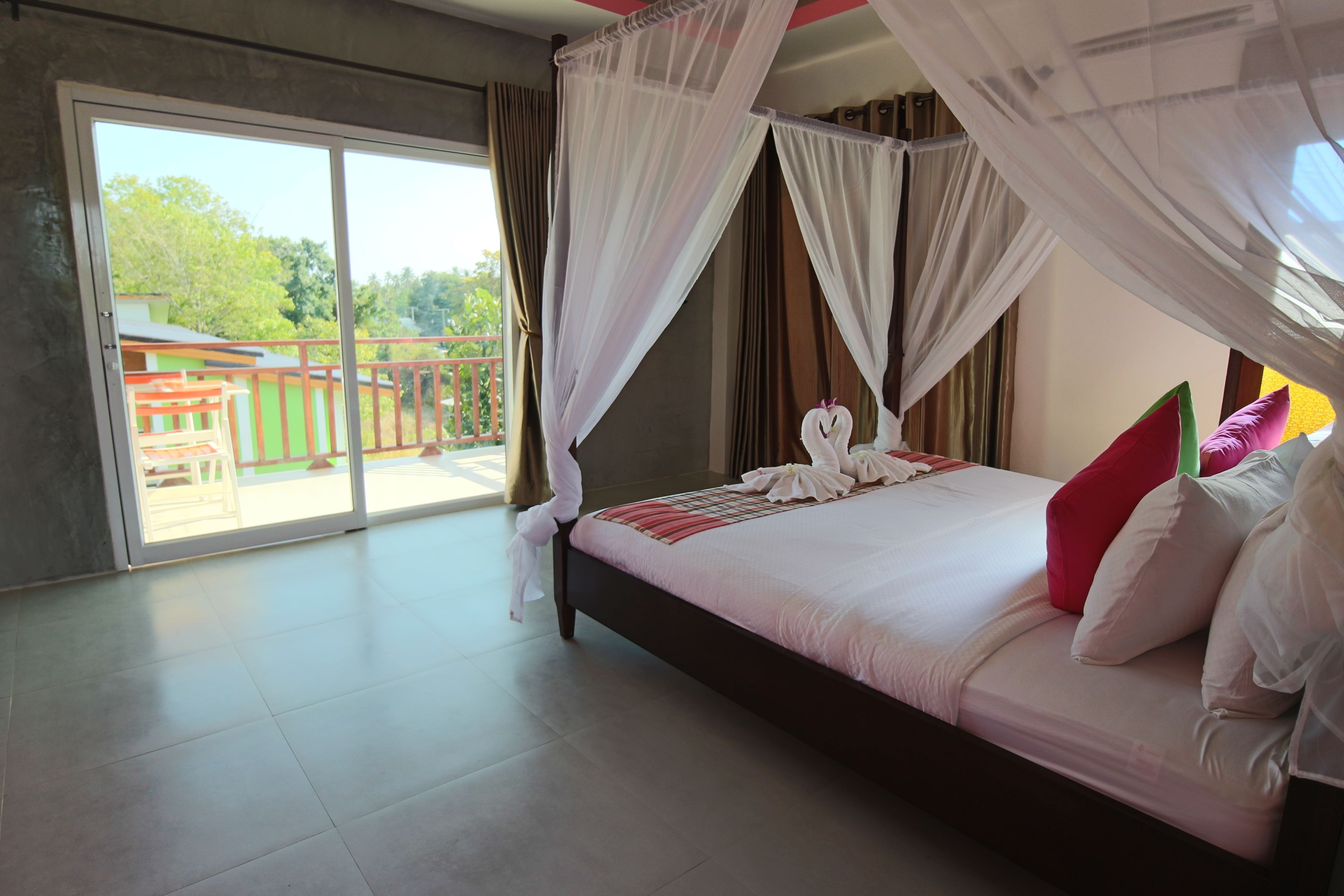 A spacious bedroom with a large bed, a balcony, and a view of the outdoors.