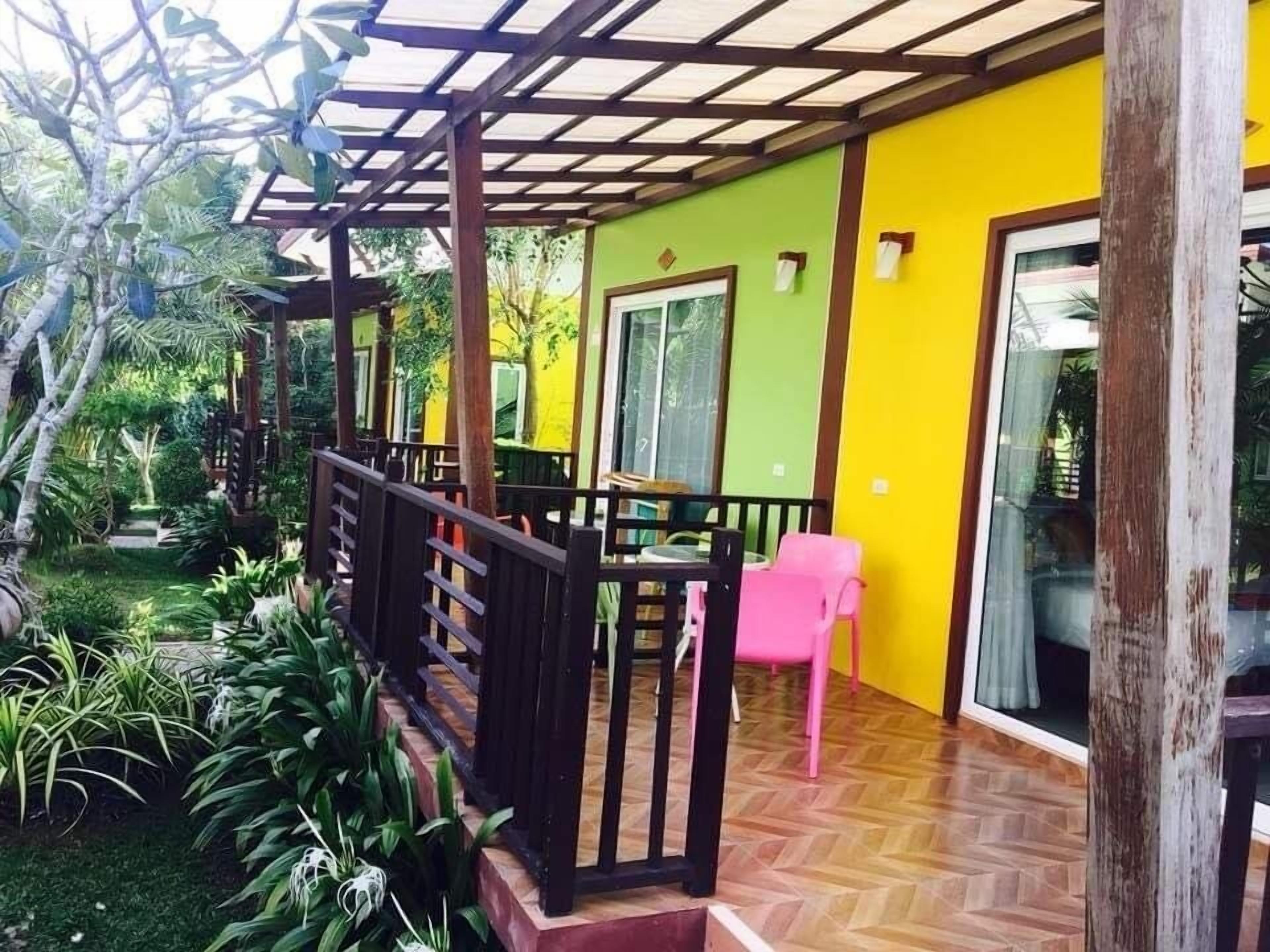 Un patio couvert doté d’une rambarde en bois, d’une chaise rose et d’un sol orné d’un motif en chevrons.