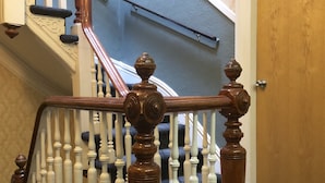 Eine Holztreppe mit weißen Balustraden und einem braunen Geländer, die zu einer Tür mit der Nummer 26 führt.