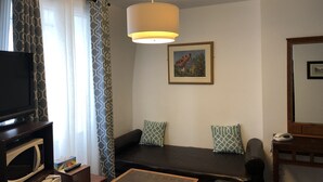 Ein Wohnzimmer mit einer Couch, einem Tisch, einem Fernseher, einer Mikrowelle und einem gerahmten Bild an der Wand.