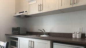 Eine Küche mit weißen Schränken, einer Edelstahl-Spüle, einer Mikrowelle und einem Toaster.