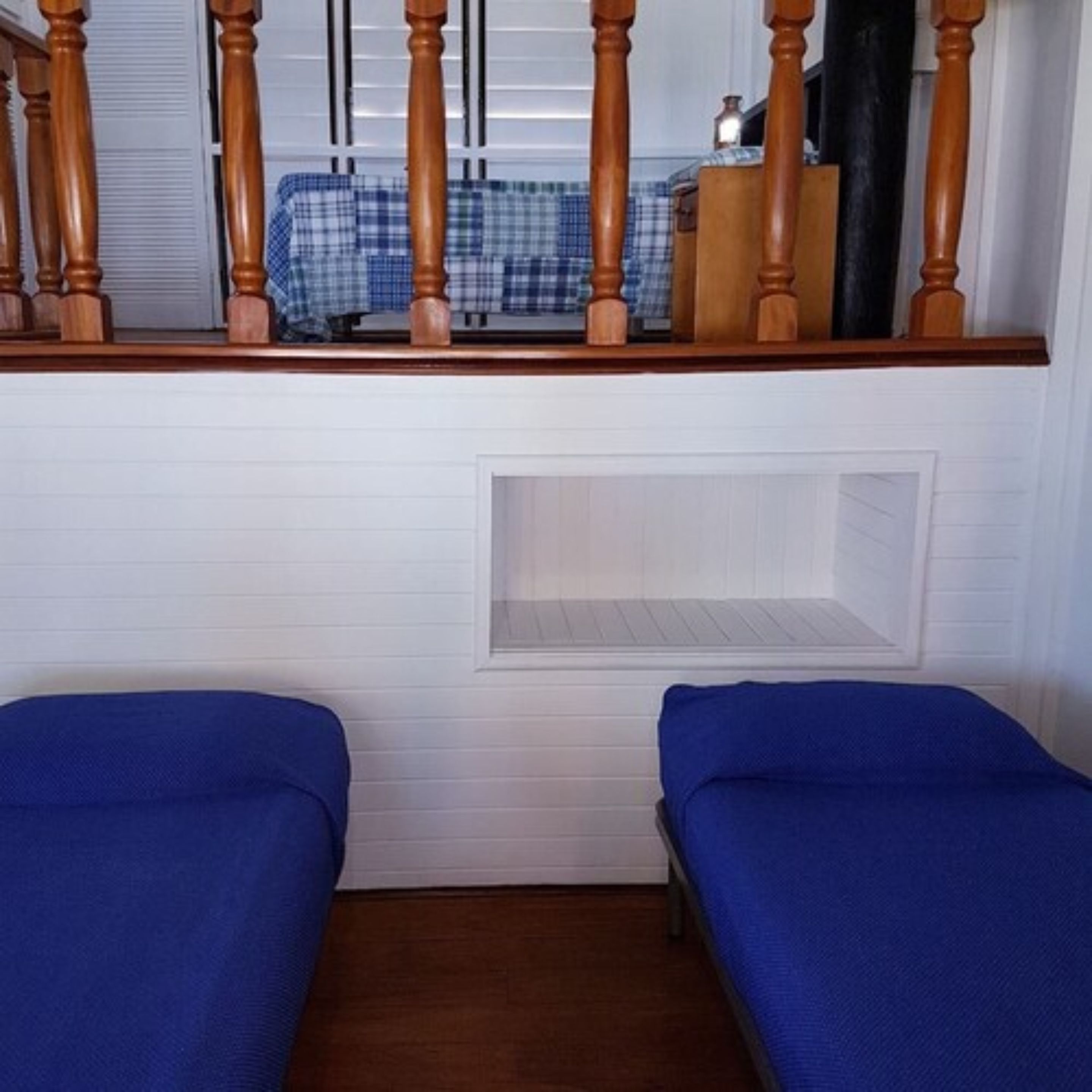 Una stanza con due letti singoli, una scala in legno e una finestra con tende.