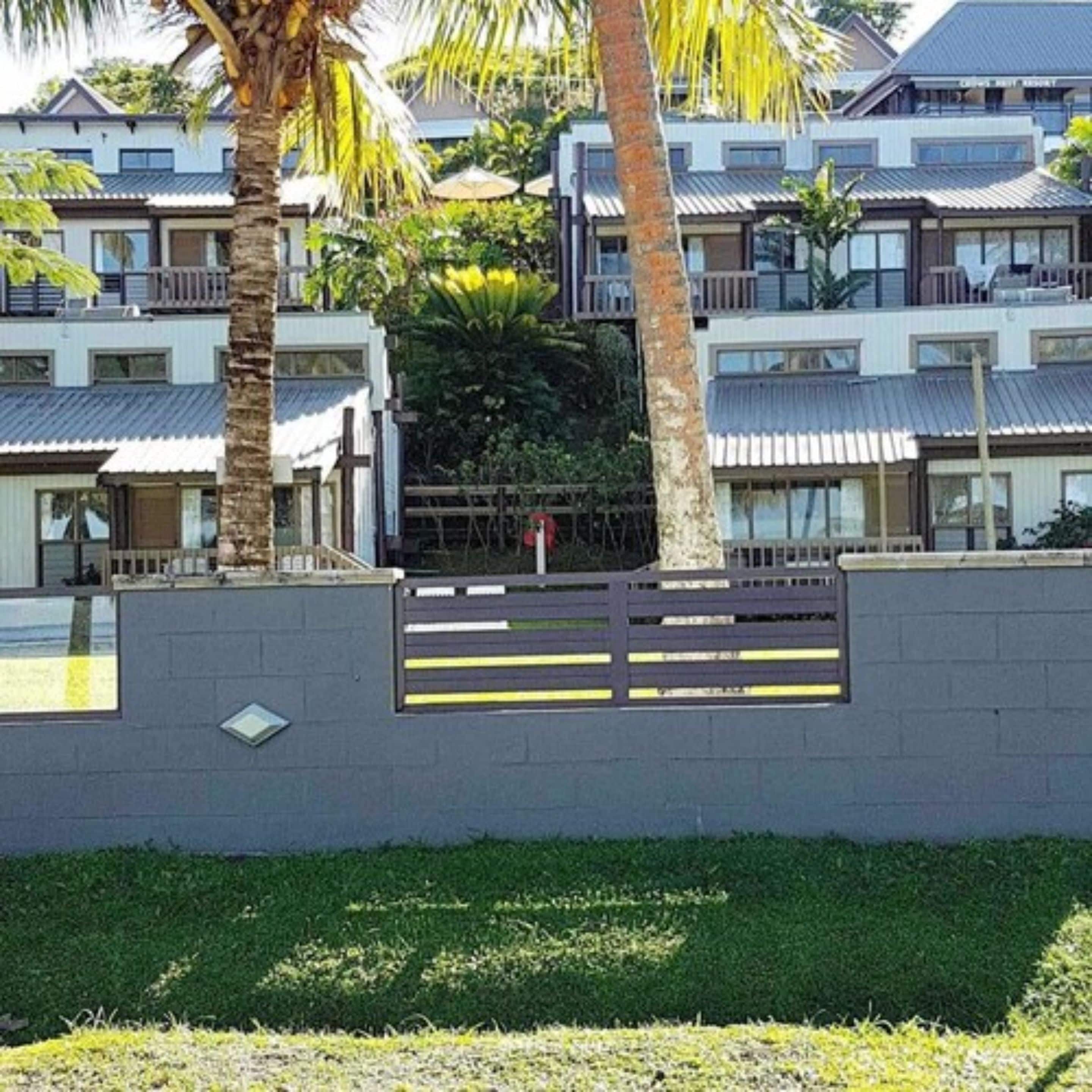 Un edificio moderno con varios balcones y una entrada protegida por un portón.