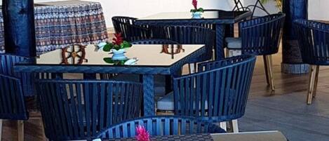 Un restaurante con una mesa central rodeada de sillas, un mantel estampado y detalles decorativos en las paredes.