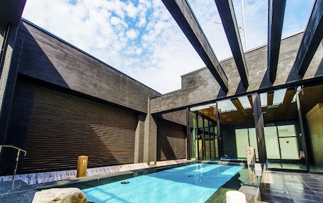 A modern building with a swimming pool, large windows, and a covered area.