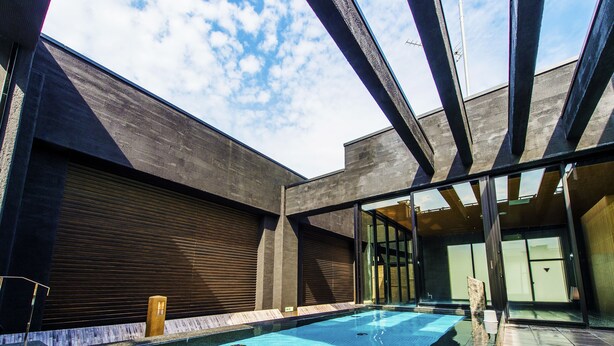 A modern building with a swimming pool, large windows, and a covered area.