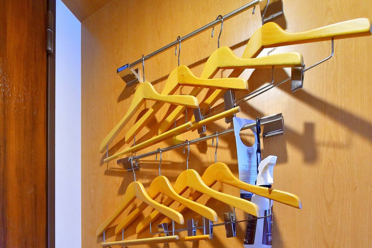 Eine Holzwand mit einem Metallgestell, das mehrere gelbe Kleiderbügel hält.