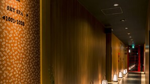 A hotel corridor with a floral wallpaper, a reception desk, and a row of illuminated signs.